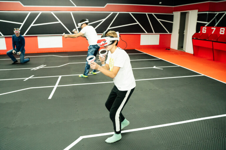 Игроки в VR-очках участвуют в VR-турнире по фиджитал-спорту в Пензе, демонстрируя азарт и сосредоточенность.